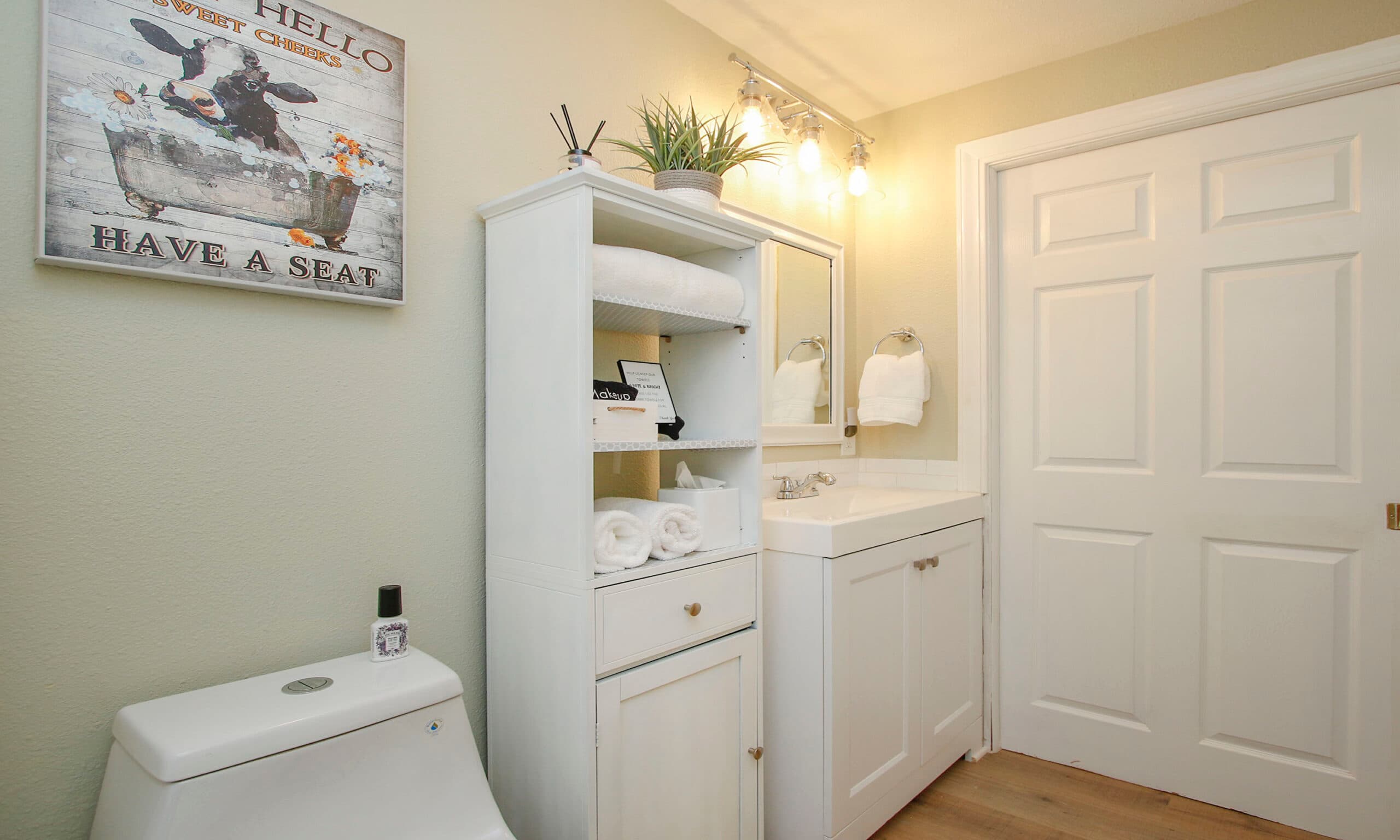 Tiled bathroom with vanity, fresh towels, and cow painting decor