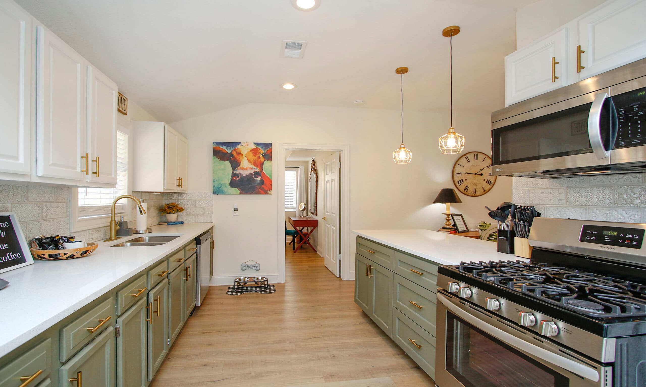 Kitchen with gas range, pendant lights, and cow painting