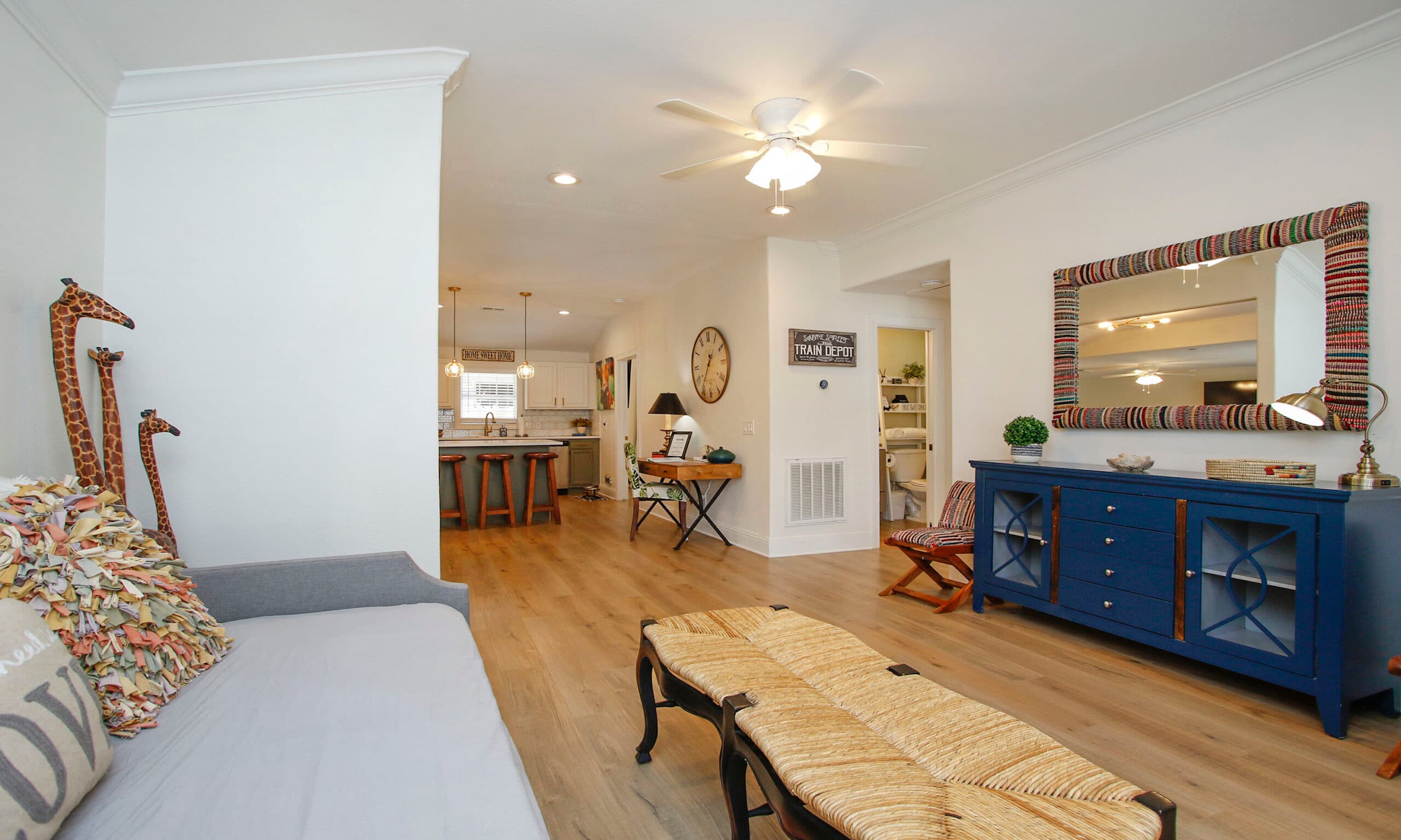 Living room with blue cabinet, colorful mirror, and hardwood floors