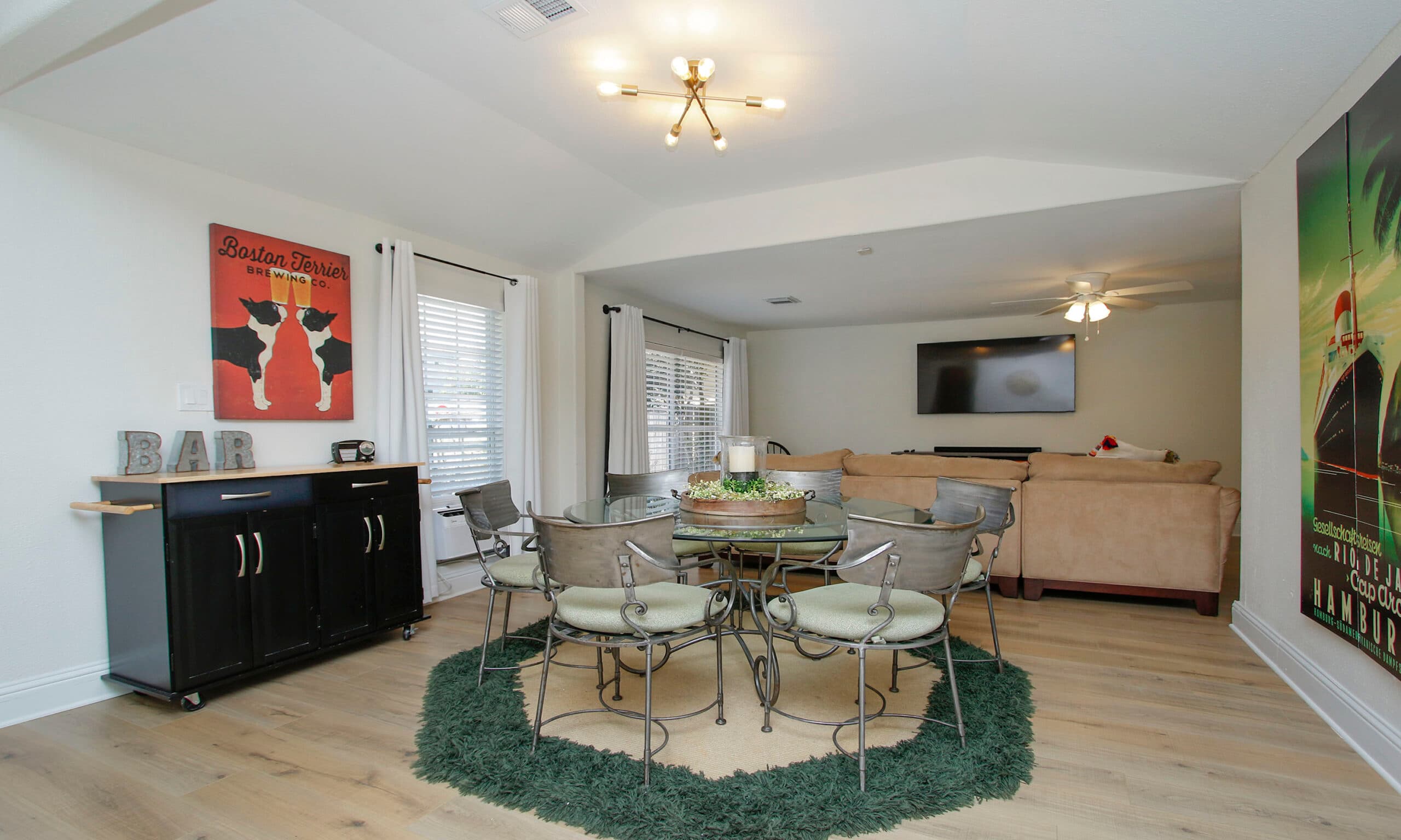 Dining area with glass table and den with sectional sofa and smart TV